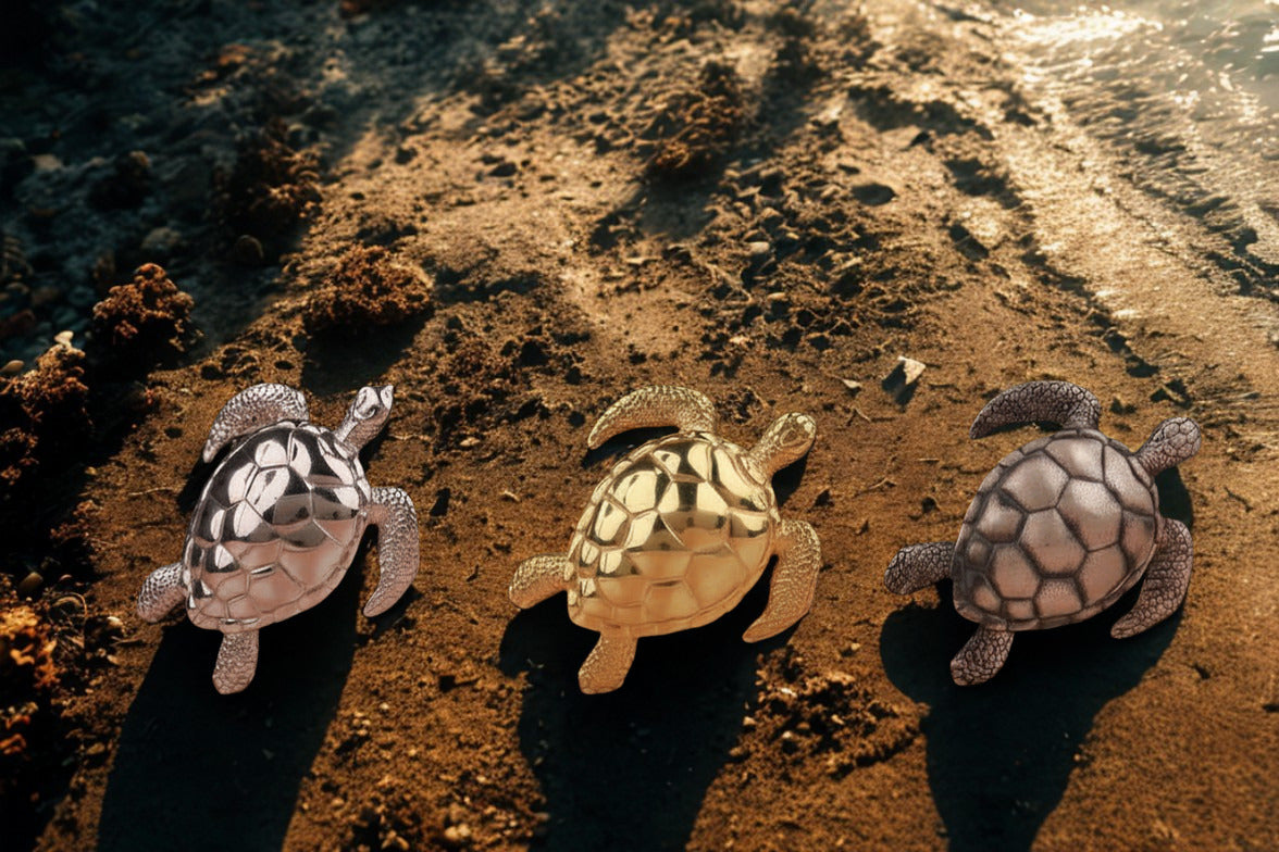 Three sea turtle pendants in different finishes on beach