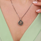 Necklace with a Virgin Mary pendant worn by a person against a green background
