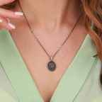 Necklace with a st michael pendant worn by a person against a neutral background