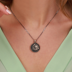 Necklace with an athena coin pendant worn by a person against a neutral background