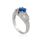Square cut blue gemstone on skull ring against white background