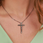 An oxidized sterling silver necklace with a Catholic cross pendant worn by a person