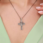An oxidized sterling silver crown of thorns jesus cross pendant necklace on a person wearing a green top