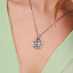 An oxidized pendant with Janus pattern worn by woman with green dress 