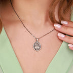 Silver necklace with a jesus pendant worn by a person against a neutral background