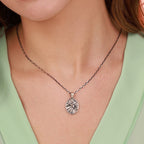 Close-up of a necklace with a crown of thorns jesus pendant on a person wearing a light green top.