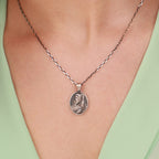 Silver necklace with a good shepherd pendant on a person wearing a light green top.