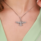 Silver necklace with a detailed faravahar pendant on a person wearing a green top.