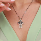 A sterling silver cross pendant necklace featuring an embossed figure of Jesus Christ, worn by a model in a mint green top.