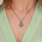 Silver Virgin Mary necklace with a pendant worn by a person in a green top