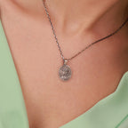 Silver necklace with a jesus crown of thorns pendant on a person wearing a green