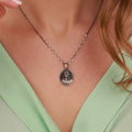 Silver necklace with a jesus pendant worn by a person in a green top