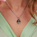 Silver necklace with a jesus pendant worn by a person in a green top
