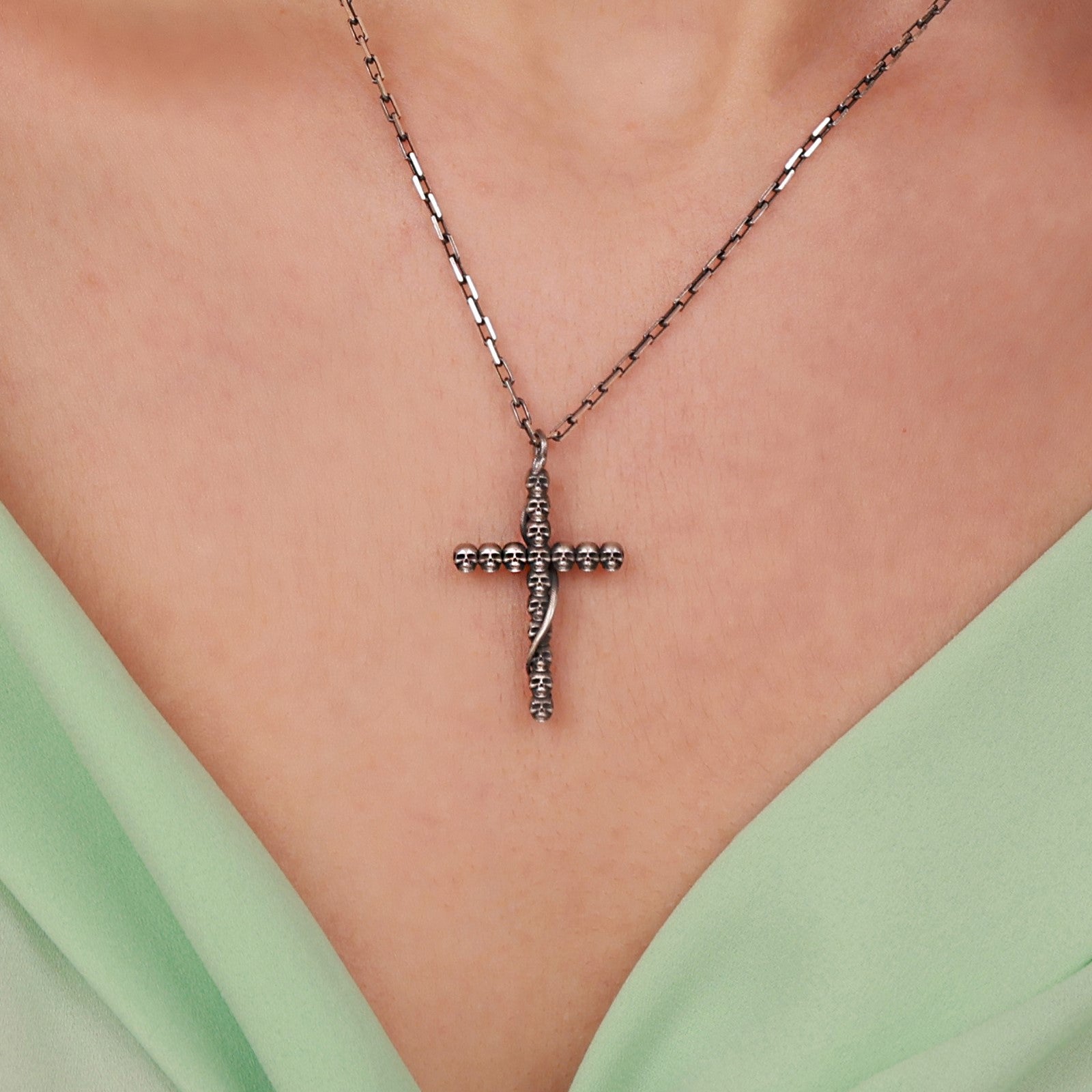 Sterling Silver gothic cross necklace on a person wearing a light green top