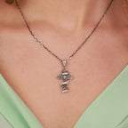 A sterling silver cross pendant necklace with filigree details and the "Only God Can Judge Me" phrase, worn on a model's neck over a light green top.