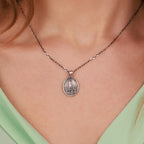 Necklace with a catholic pendant worn by a person, focusing on the jewelry against a neutral background.