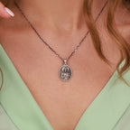 An oxidized st jude necklace worn by woman with green
