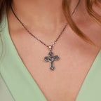 A close-up of a person wearing an oxidized sterling silver cross pendant necklace with a detailed St Michael the Archangel, styled with a mint green top.