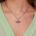 Necklace with a sword pendant featuring wings on a person wearing a light green top.
