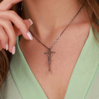 A sterling silver necklace with a crucifix pendant worn by a person in a green top.