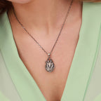 Silver Egyptian god pendant necklace on a person wearing a light green top.