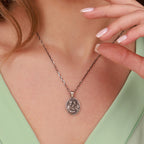 Necklace with a holy family pendant worn by a person, against a neutral background