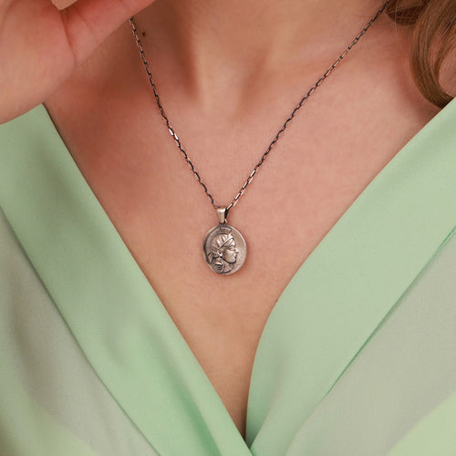 Necklace with an athena pendant worn by a person in a light green top