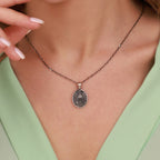 Necklace with an Our Lady of Charity pendant worn by a person, focusing on the jewelry against a neutral background.