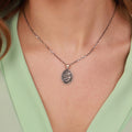 Necklace with a jesus in prayer pendant worn by a person in a light green top