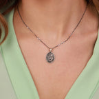 Necklace with a jesus in prayer pendant worn by a person in a light green top