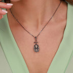 Necklace with a bastet pendant worn by a person in a light green top