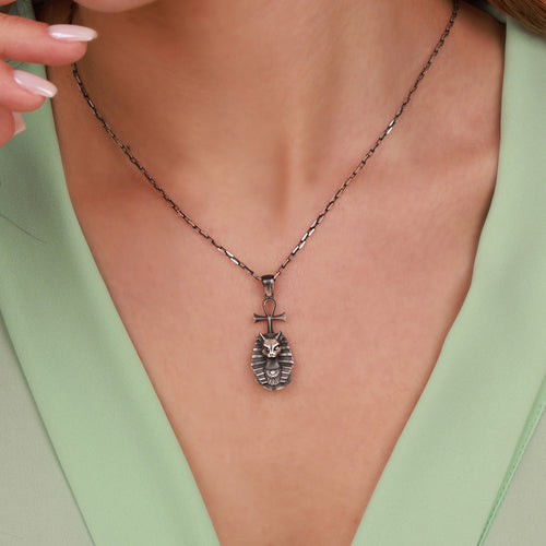Necklace with a bastet pendant worn by a person in a light green top