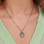 Necklace with a Good Shepherd pendant worn by a person against a light green background