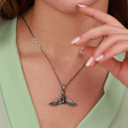Silver necklace with a winged isis pendant worn by a person against a light green background