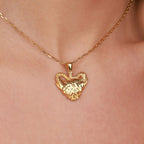 Gold necklace with two elephant in a heart-shaped pendant on a person's neck