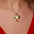 Gold elephant pendant necklace on a person wearing a red top