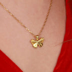 A gold necklace with a butterfly-shaped pendant on a person wearing a red top.