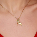 A gold necklace with a swallow-shaped pendant on a person's neck