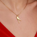 A gold necklace with a parrot-shaped pendant on a person wearing a red garment.