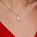 A gold necklace with a parrot-shaped pendant on a person wearing a red garment.