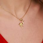 Gold flamingo pendant necklace on a person wearing a red top.