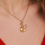 Gold swan pendant necklace on a person wearing a red top