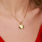 A gold elephant pendant necklace on a person wearing a red top