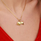 A gold necklace with a Taurus bull pendant on a person wearing a red top.