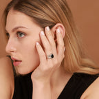 Woman wearing a black ring on her finger against a brown background