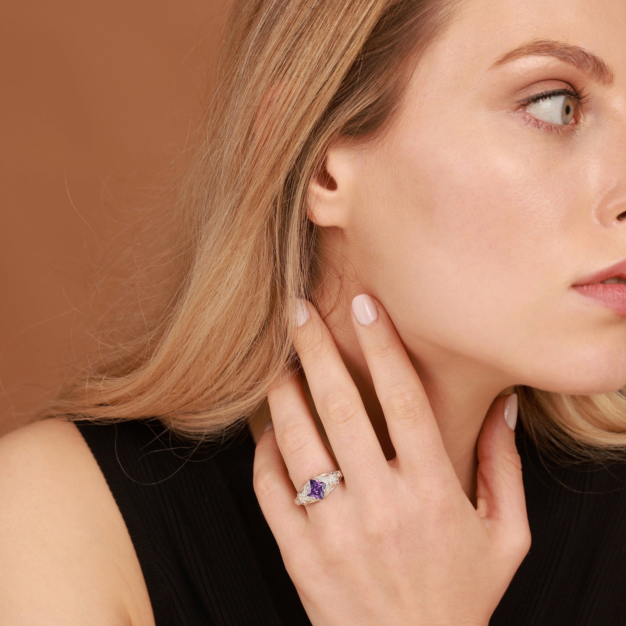 Woman wearing a purple amethyst gemstone ring on a brown background