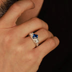 Hand wearing a polished silver ring with a blue gemstone against a dark background