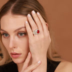 Woman wearing a ring with a red gemstone against a brown background