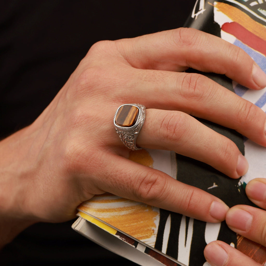 Hand with a silver gemstone ring holding a colorful book or notebook