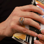 Hand with a silver gemstone ring holding a colorful book or notebook